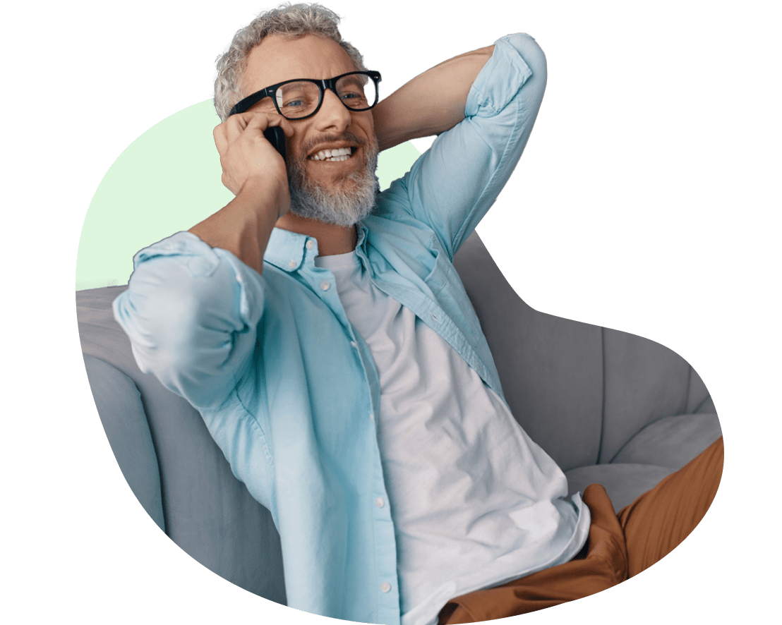 Man smiling and laughing on his phone while at home.